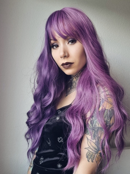 This two tone split colour wig has 1 half violet and on the other side a muted purple. The blunt fringe carries the colours seamlessly. Long with loose barrel curls for volume.