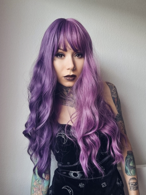 This two tone split colour wig has 1 half violet and on the other side a muted purple. The blunt fringe carries the colours seamlessly. Long with loose barrel curls for volume.