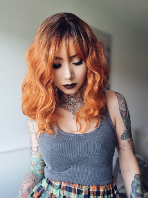 Firestorm with dark brown shadowed roots runs into a ginger tone thats hard to ignore. This natural ginger look id styled into volumes of waves with a fringe to frame the face.