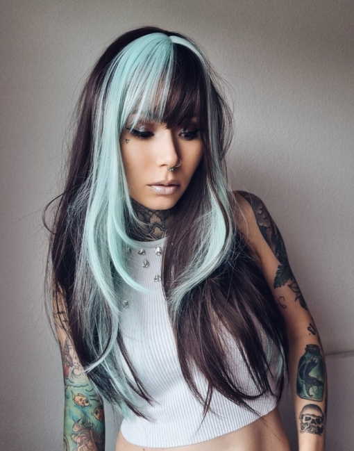 Draven is styled into a sleek blowout, with blunt bangs. Layers that frame the face with a mix of mint green and dark brown. With a block of colour from the nape of the neck, to give a peek-a-boo effect.